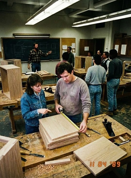 Woodworking class measuring boards and learning furniture construction in a workshop