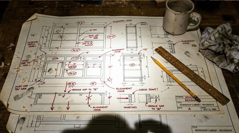 Detailed cabinet woodworking blueprint with handwritten measurements, ruler and pencil on a workbench